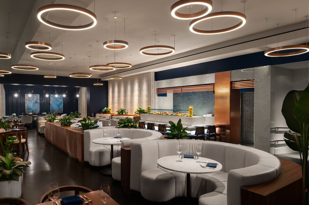Modern restaurant interior with curved white booths, circular pendant lighting, and a service counter.