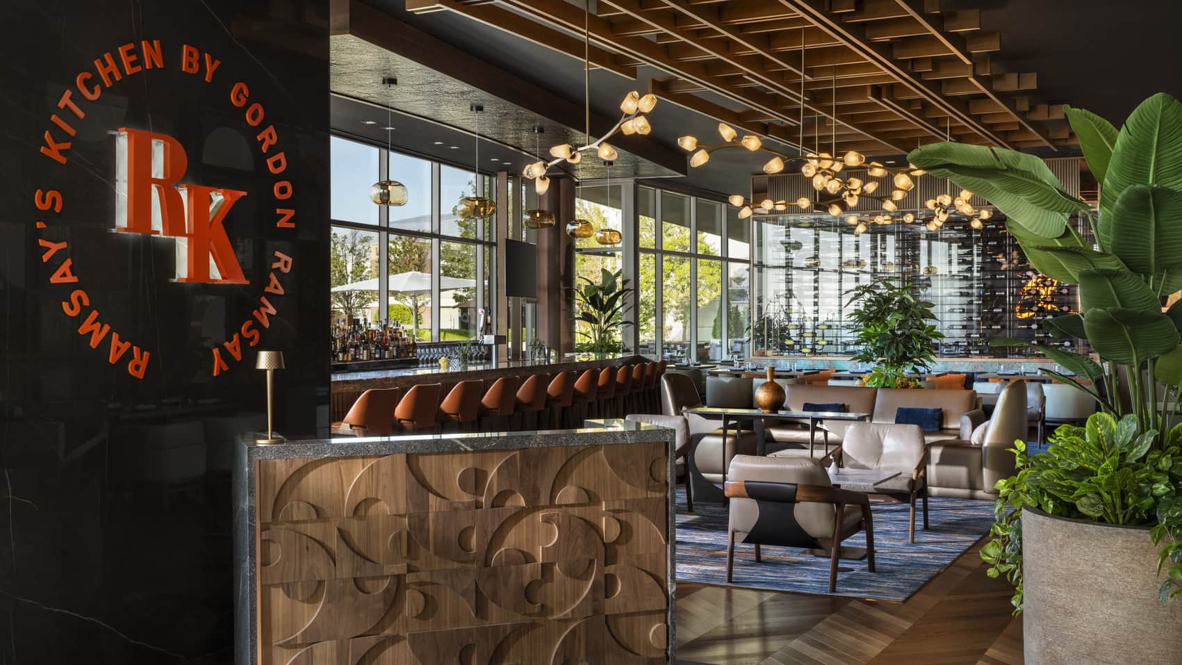 Interior of Ramsay’s Kitchen restaurant featuring a branded sign, a bar area, and dining tables.