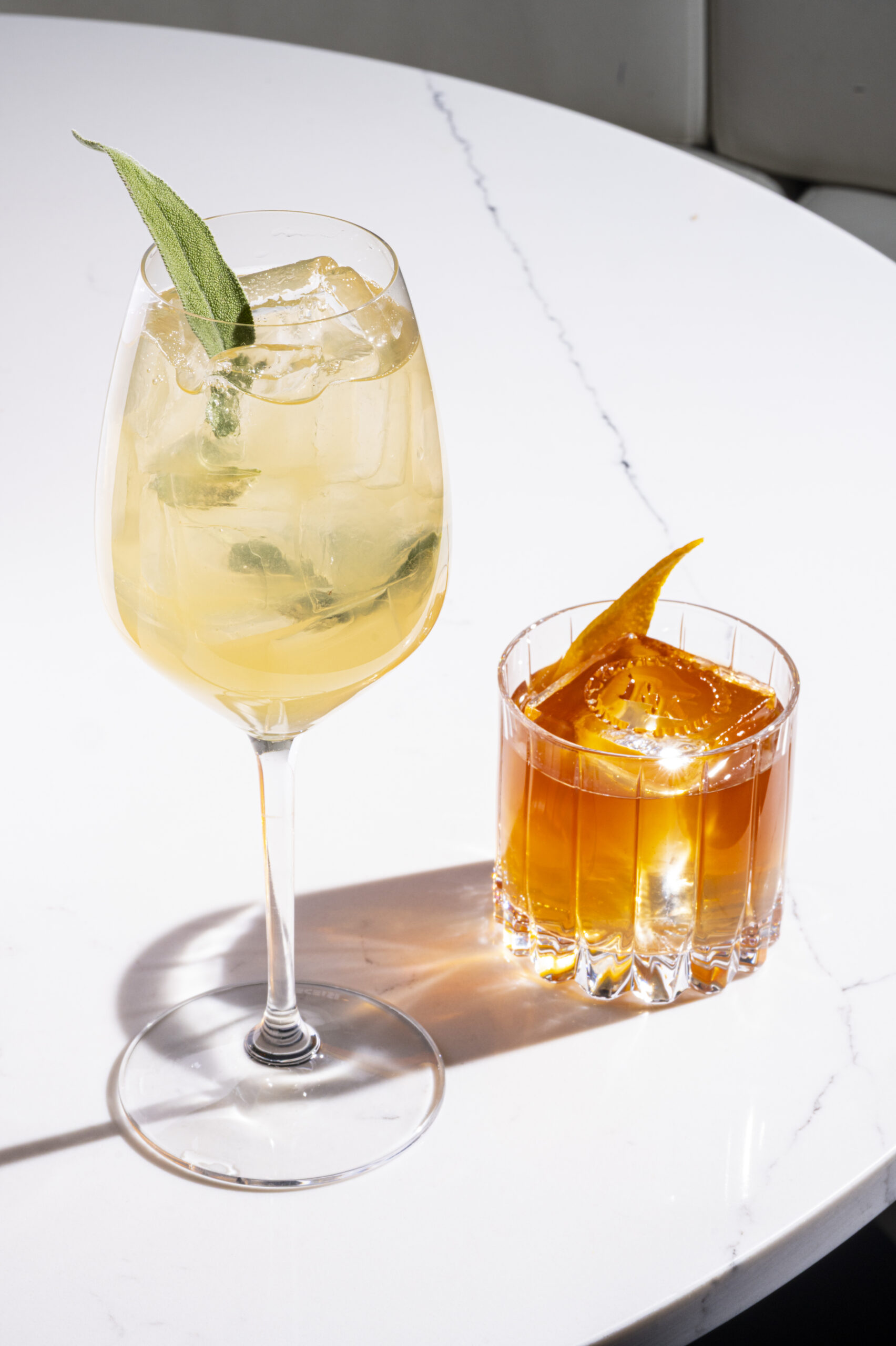 Four cocktails garnished with fruit on a marble counter.