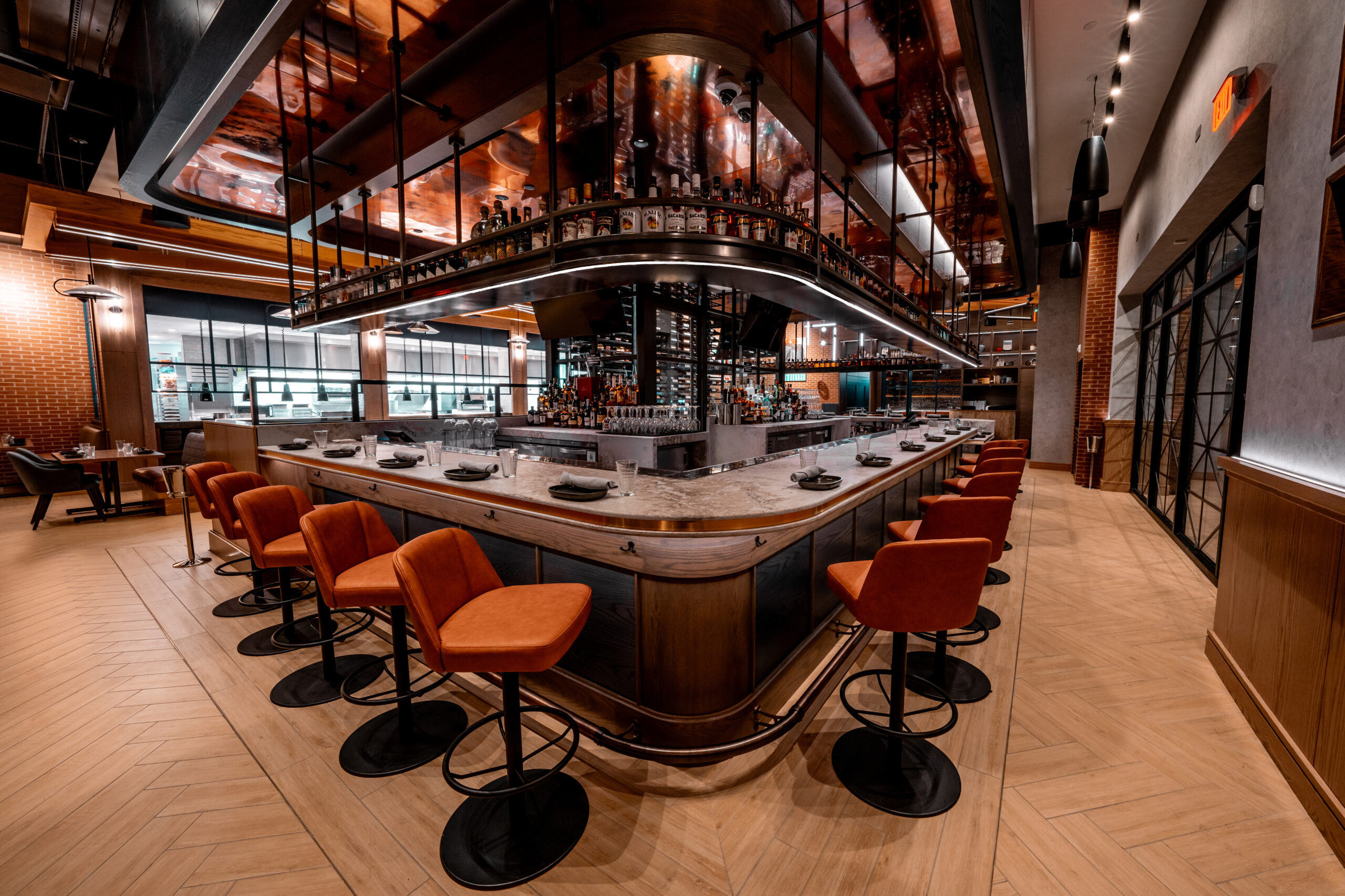 A curved bar with orange stools in a modern restaurant interior.
