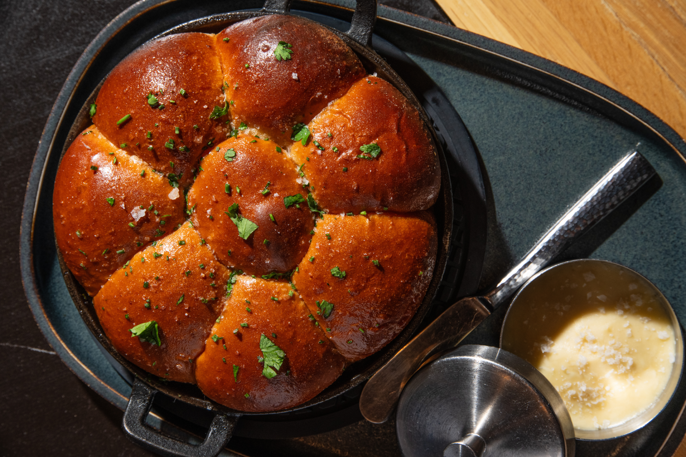 A pull-apart bread roll served in a small cast-iron frying pan with a side of butter.