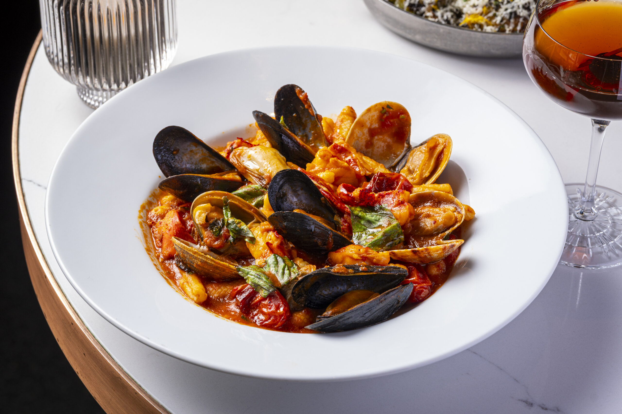 A bowl of seafood pasta with mussels and clams in a tomato-based sauce.